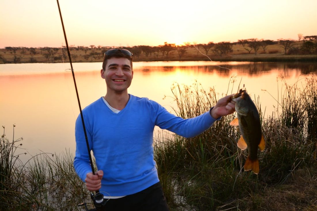 Alex holding a bass at sunset, South African highveld